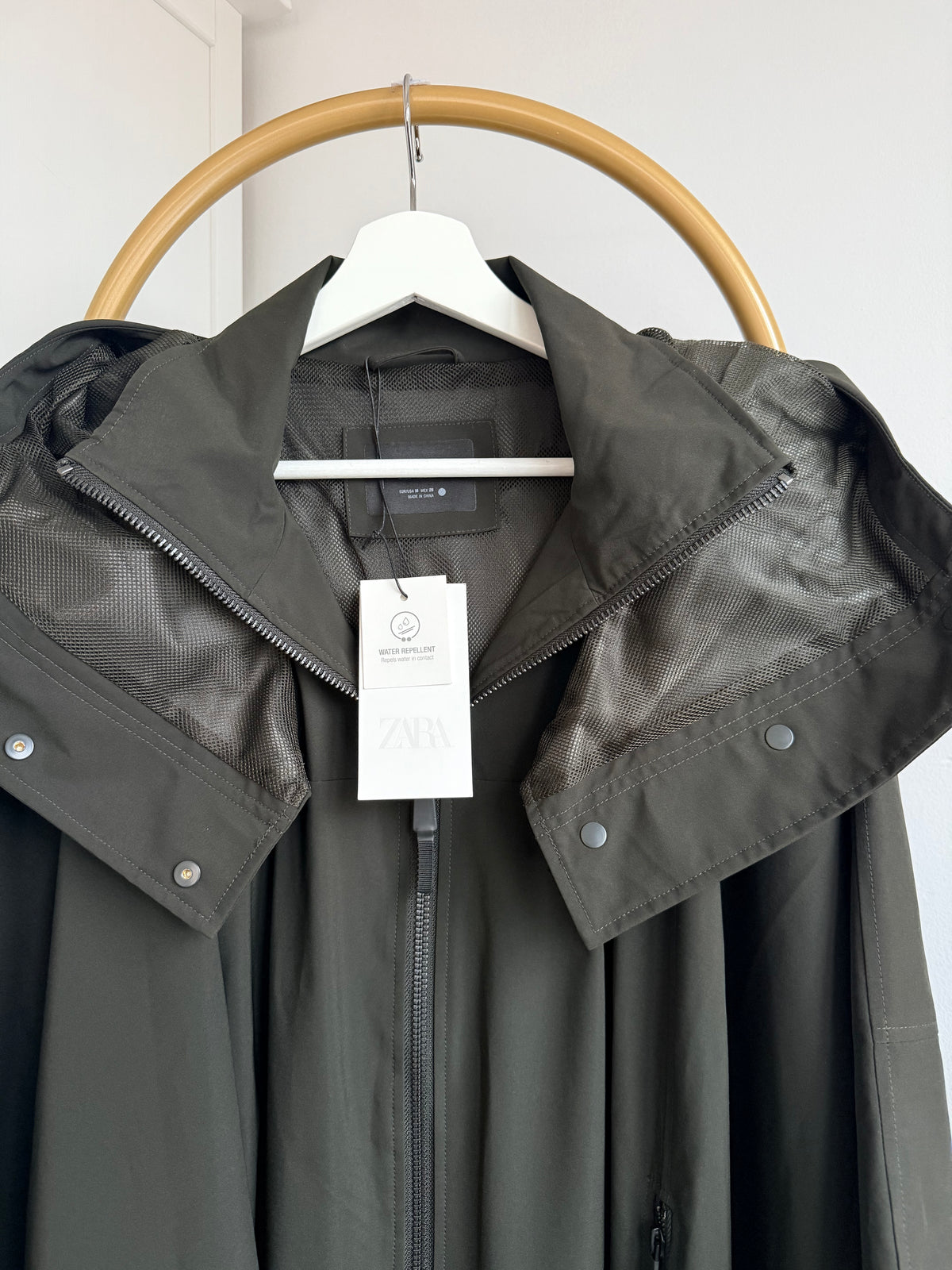     Close-up front view of Zara khaki cape rain coat showing hood and neckline