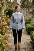     Woman wearing Zara grey belted knit jumper with black trousers outdoors